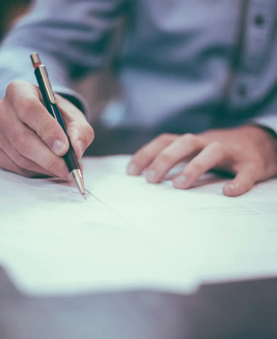 A man signs a contract at a desk