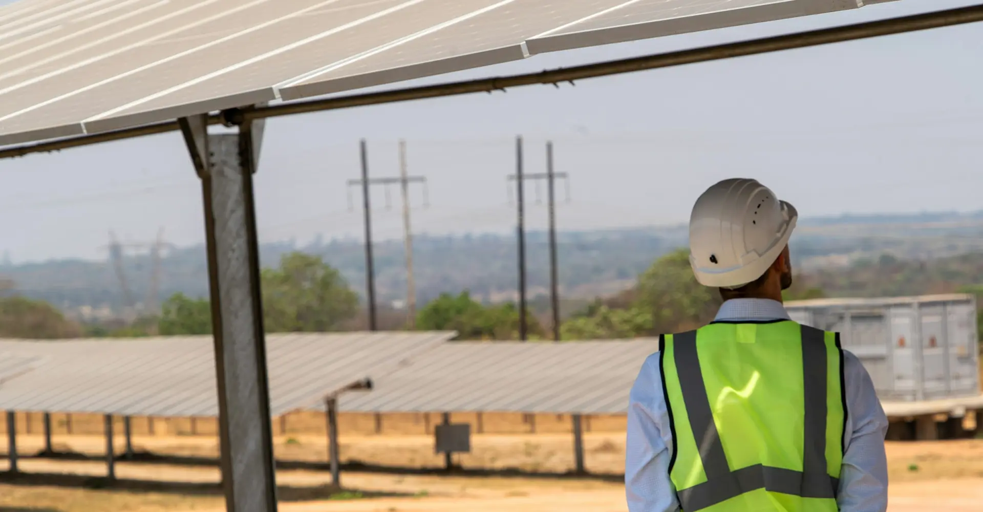 Engineer in a safety vest beneath solar panels